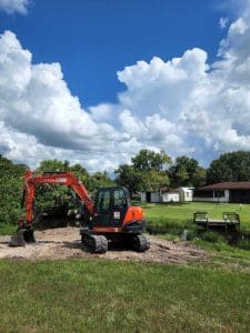 Orange excavator parked on grassy field.