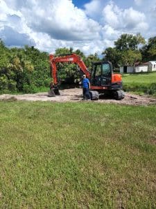 Man standing near a red excavator.