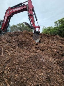 Red excavator loading wood chips.