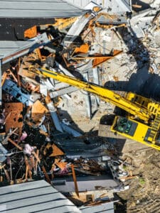 Demolition excavator clearing debris from building.