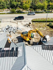 Excavator demolishing a metal roof.