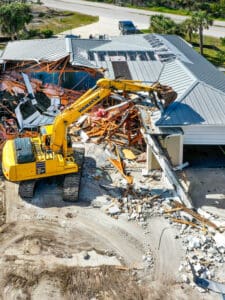 Excavator demolishing a house with debris.