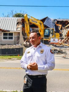 A firefighter standing in front of a demolished building.